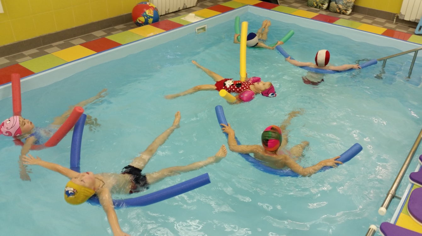 baseins, kurā notiek nodarbība - bērni peld ar nūjām